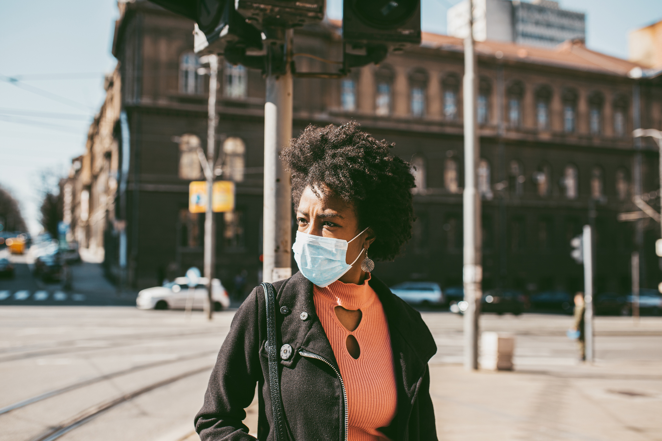 woman walking in city wearing protective coronavirus face mask