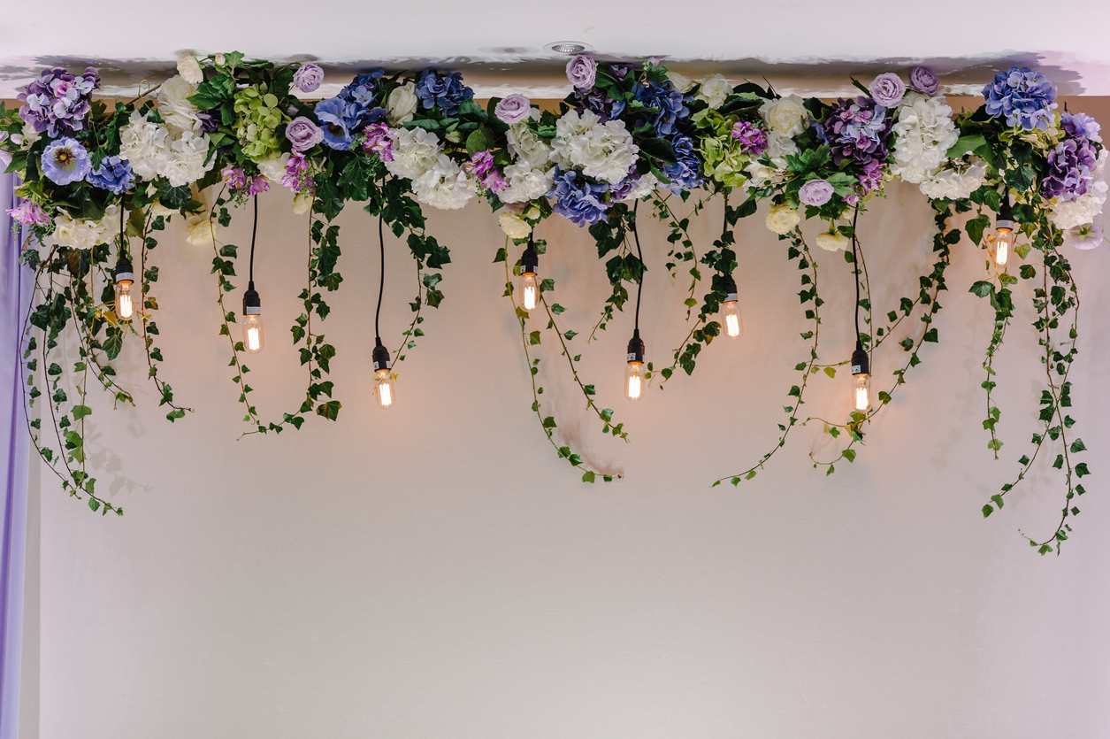 Beautiful decor made with garland with luminous lamps and floral decorations. Decor of flowers on wedding ceremony.