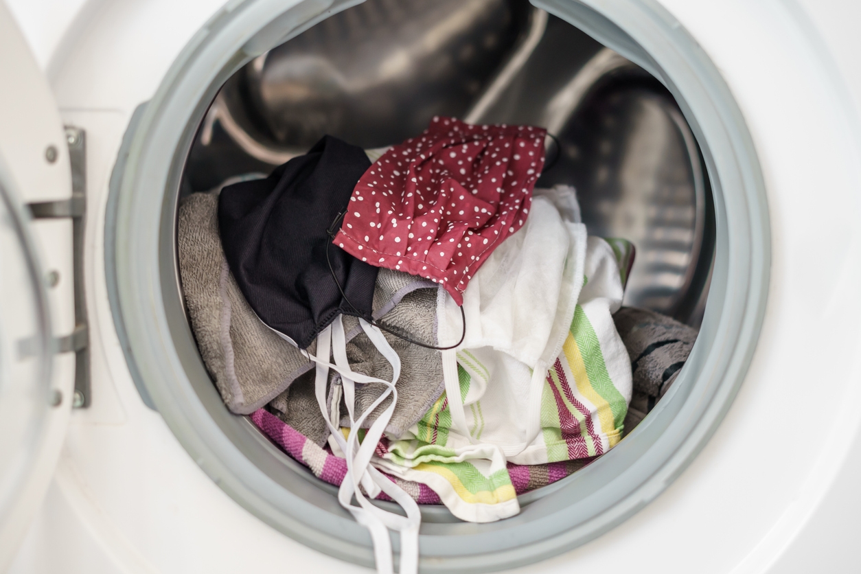 Face mask and dirty laundry in a washing machine, close-up